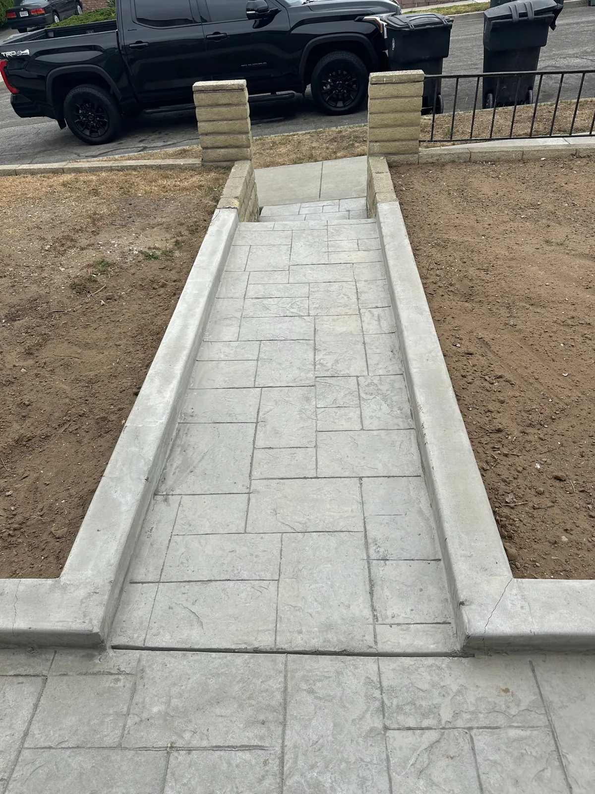 Stamped concrete walkway with stone-capped pillar entry